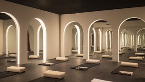 A yoga studio with multiple mats and cushions, illuminated by arch-shaped lighting. - Silvestre Nosara, Hotel & Residences (Nosara)