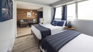 Ein Schlafzimmer mit zwei Betten, einem Sofa, einem Fernseher und einem Fenster mit Vorhängen.
