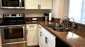 A kitchen with stainless steel appliances, white cabinets, and a granite countertop.
