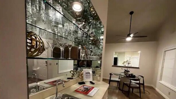 A kitchen with a stainless steel sink, a dining area with a table and chairs, and a ceiling fan.