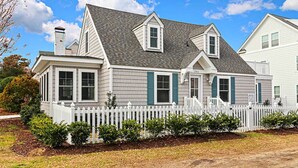 A two-story house with a white picket fence, a grey roof, and a number '201' on the front.