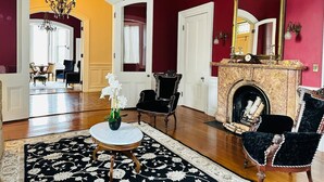 A room with a fireplace, a chandelier, and a large mirror. - The Hamilton Hoppin House (Middletown)