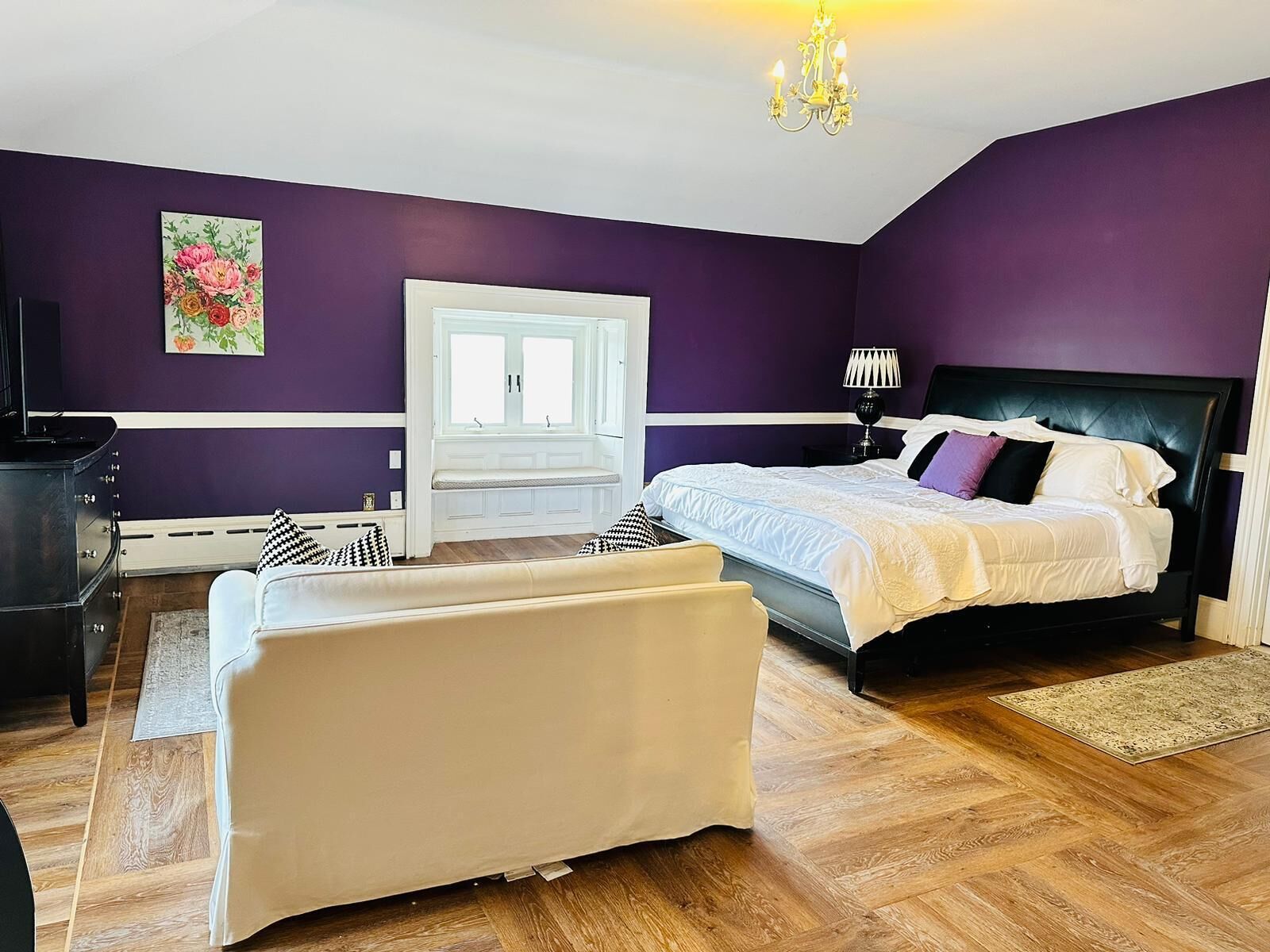 A bedroom with a bed, a bench, a dresser, and a television.
