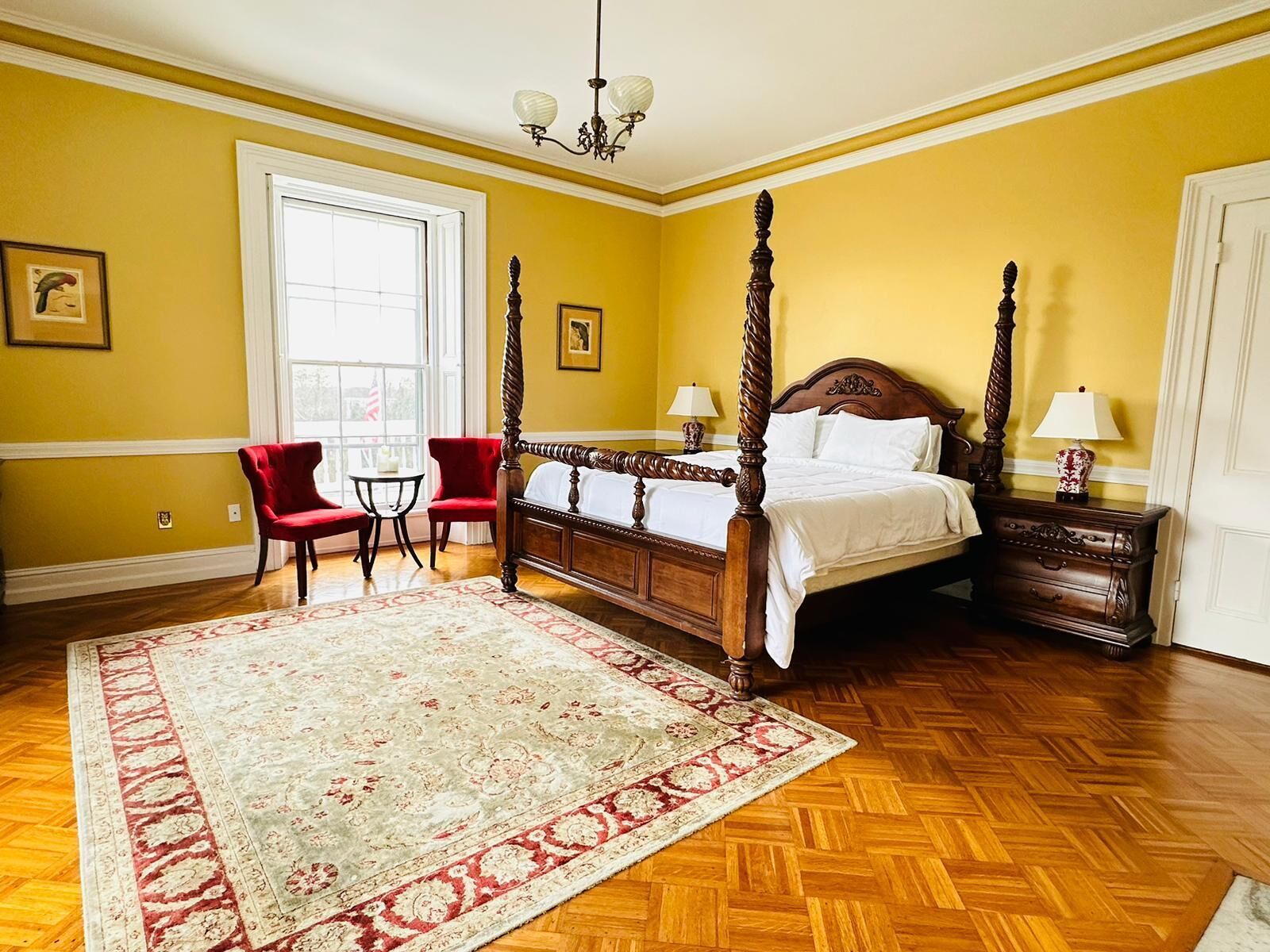 A four-poster bed in a room with yellow walls and wooden flooring.