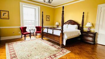 A four-poster bed in a room with yellow walls and wooden flooring.