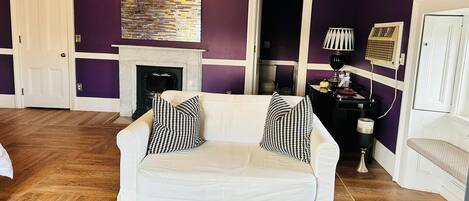 A living room with a white sofa, houndstooth pillows, a fireplace, and a modern abstract painting.