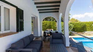 Ein überdachter Außenbereich mit Pool, einem Tisch und einer Couch.