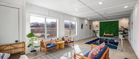 A spacious indoor area with a pool, seating, and a green wall.