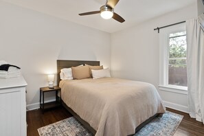 A bedroom with a bed, nightstand, lamp, and a ceiling fan. - Walkable Coffee, Restaurants, Shops, and Grocery! Huge backyard. (Columbus)