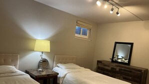 Ein Schlafzimmer mit zwei Betten, einem Nachttisch mit Lampe, einer Kommode und einem Spiegel.