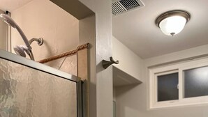 Ein Badezimmer mit Duschabtrennung aus Glas, Toilette und Waschbecken. Ein Handtuch hängt an der Wand.