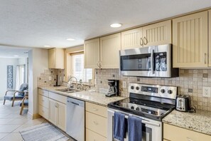 Una cocina moderna con gabinetes color beige, electrodomésticos de acero inoxidable y una encimera de granito.