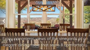 A dining area with a table seating 8, offering panoramic views of the vineyards.