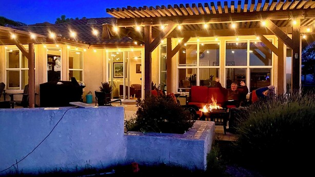 An outdoor patio area with a pergola, seating, and a fire feature.