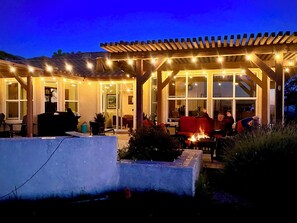 Un espace extérieur aménagé en terrasse, doté d’une pergola, de sièges et d’un foyer.