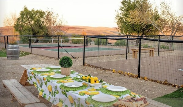 Un espace de restauration en plein air aménagé près des terrains de pickleball, avec une table pouvant accueillir jusqu'à 12 personnes.