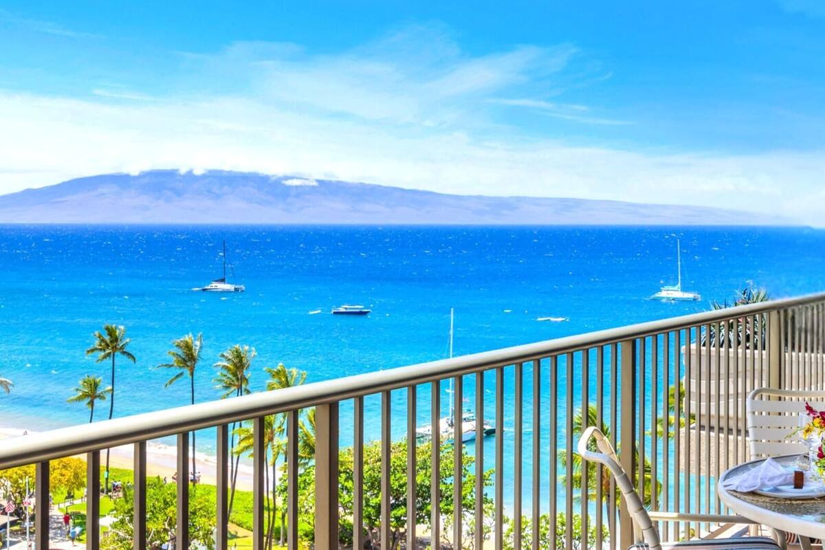 Ein Balkon mit Blick auf das Meer, Palmen und eine Berglandschaft.
