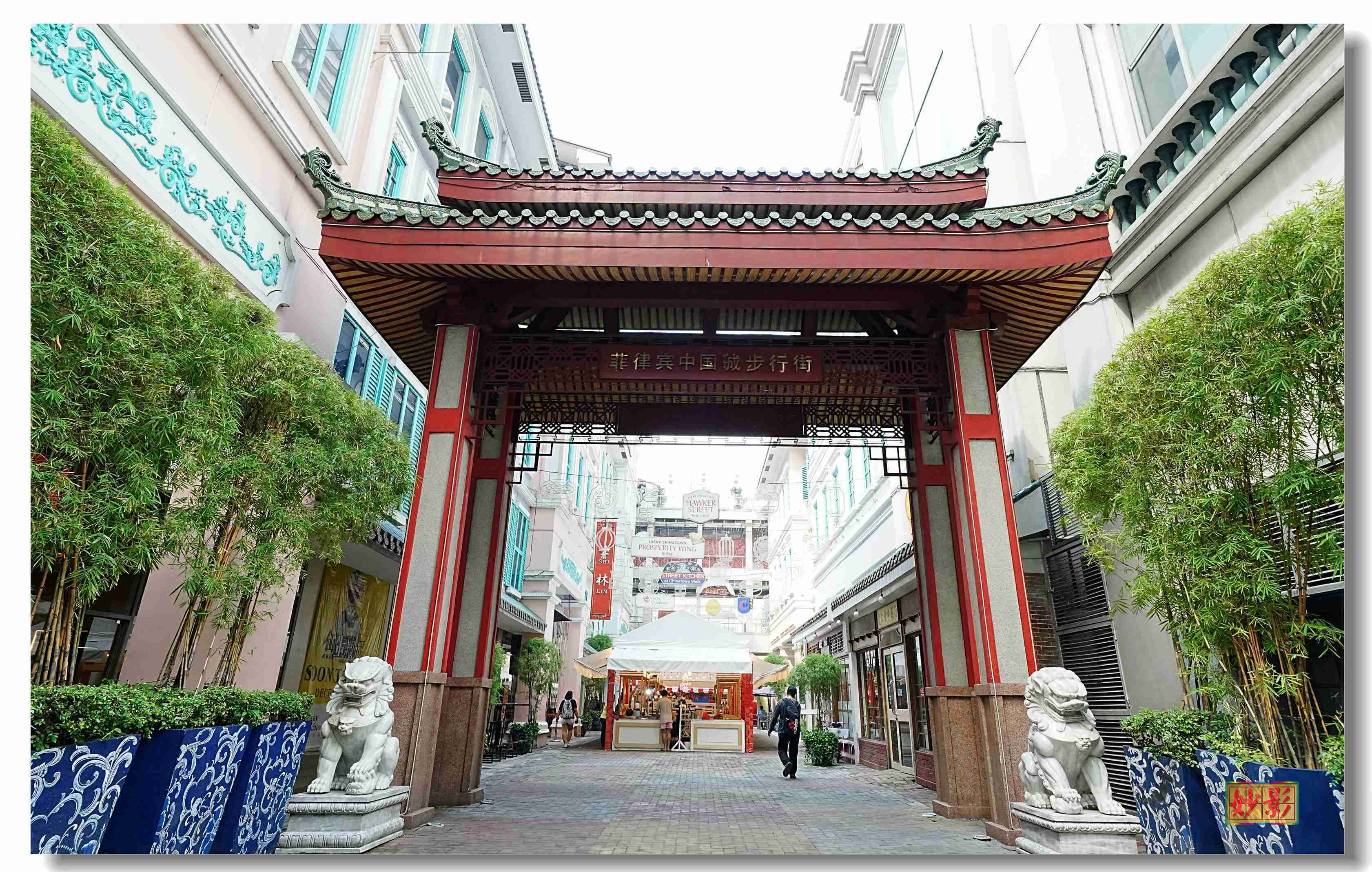 A traditional Chinese architectural entrance with a red roof and two stone lion statues on either side.