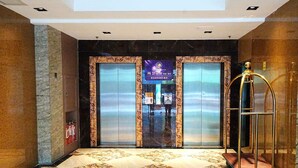 An elevator with marble walls and a patterned floor, leading to a room with a view of the sky. - Pristinehotel (Manila)