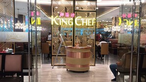 A restaurant interior with a central counter, glass partitions, and a patterned ceiling. - Pristinehotel (Manila)