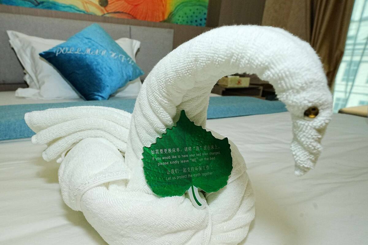 A swan-shaped towel with a message on a hotel bed.
