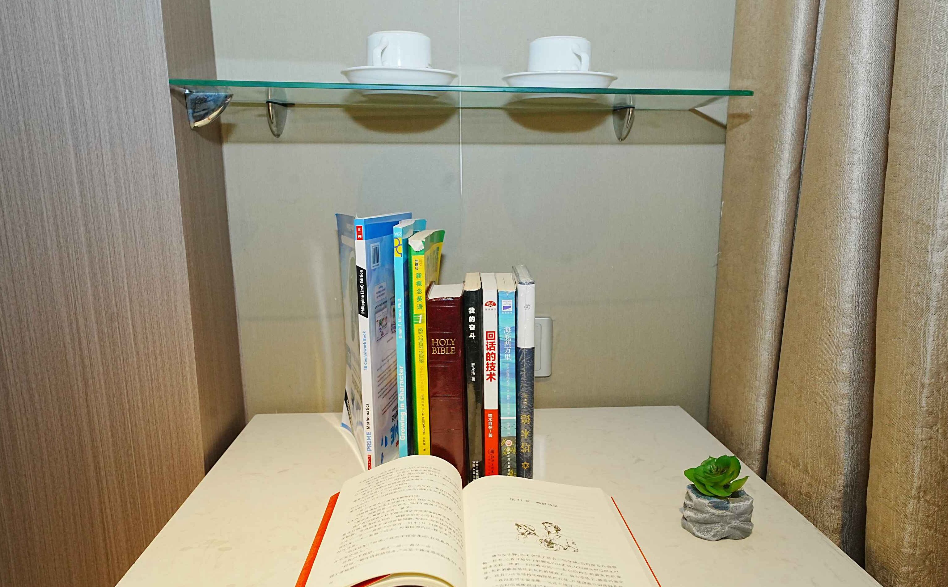 Een kamer met een glazen plank waarop boeken en twee witte bekers staan.