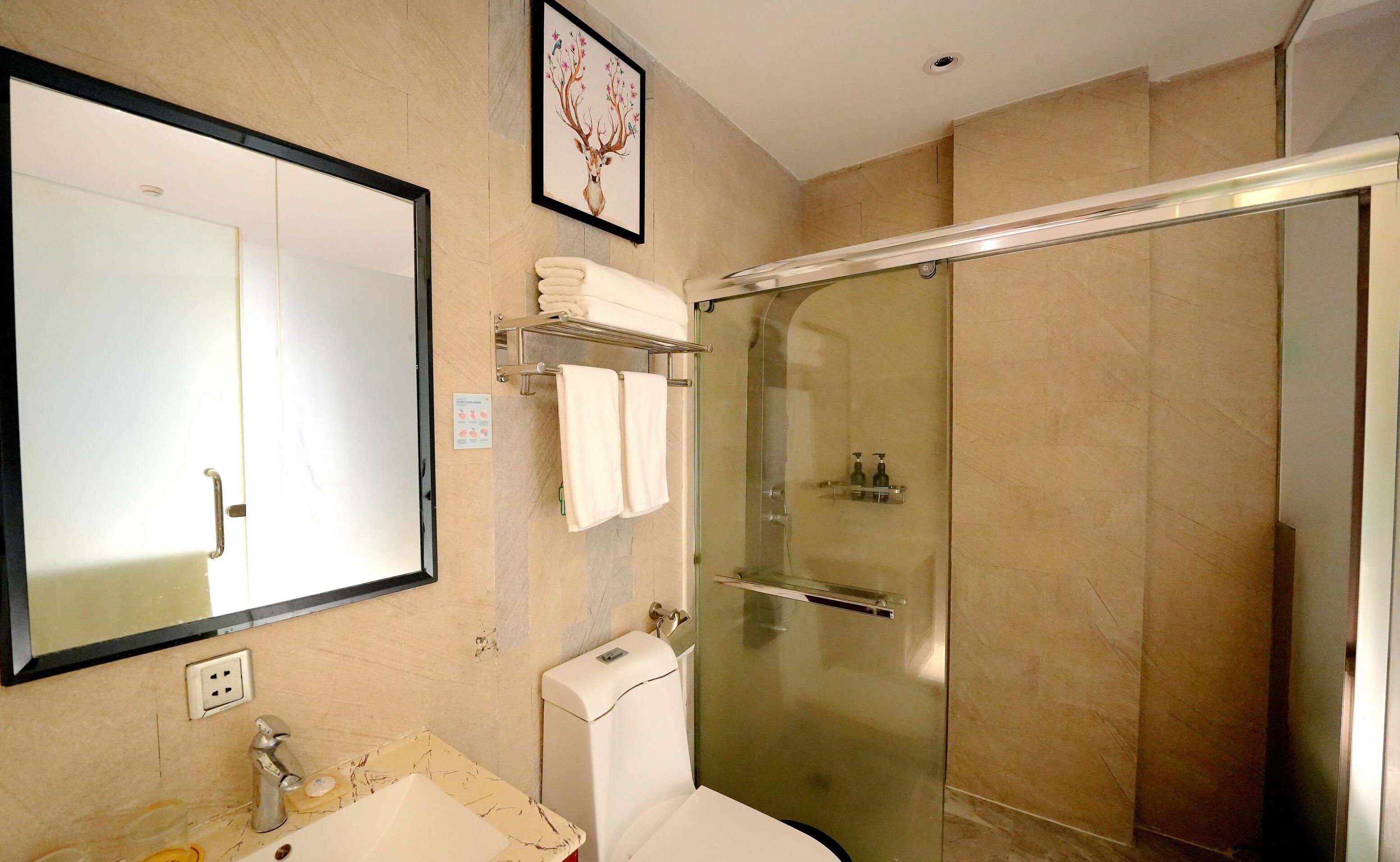 A modern bathroom with a large mirror, a glass-enclosed shower, and a toilet.