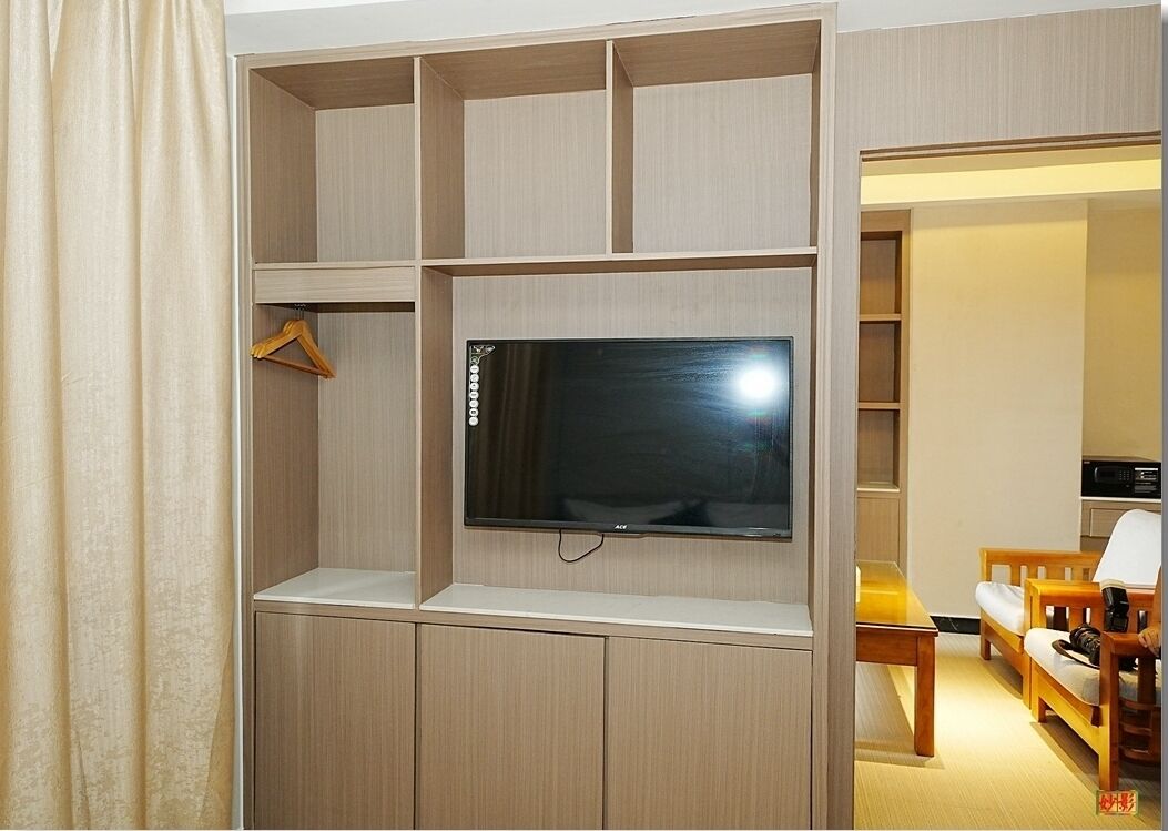 A room with a flat-screen TV mounted on a wooden wall, a wooden table, and a sofa.
