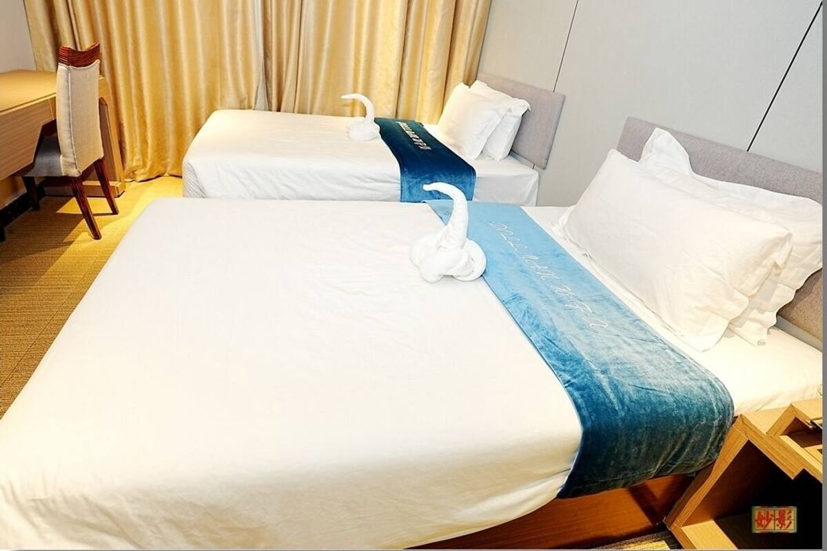 A hotel room with two beds, a desk, and a chair.