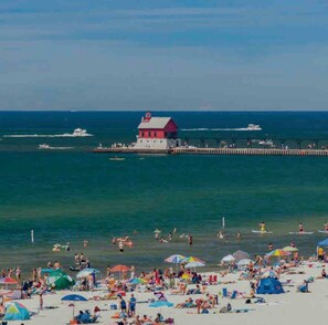 A beach with a pier and a lighthouse. - Grand Haven Getaway Welcomes You (Grand Haven)