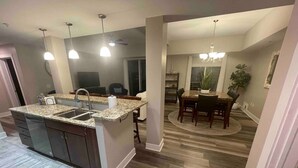 A modern kitchen with granite countertops, a central island with a sink, and pendant lighting. - Grand Haven Getaway Welcomes You (Grand Haven)