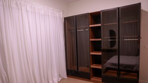 Une chambre à coucher comprenant un lit, une armoire avec plusieurs compartiments et un rideau.