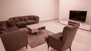 Un salon moderne avec un canapé d’angle, une table basse et un téléviseur à écran plat posé sur un meuble.
