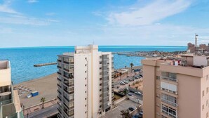 A high-rise hotel overlooking a beach with a clear view of the sea and a pier in the distance.