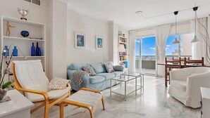A modern living room with a sofa, armchairs, a coffee table, and a view of the sea.