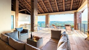 A spacious patio with wicker furniture, a glass-top table, and a view of the mountains. - Casa Leonarda 8+2, Emma Villas (Belveglio)