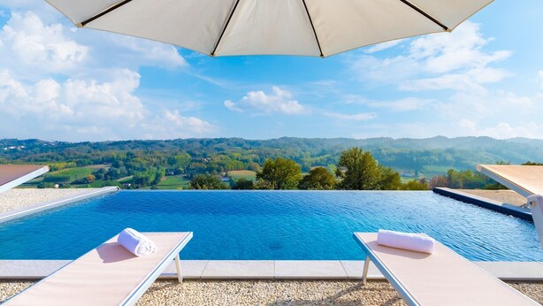 An infinity pool with a view of a green landscape and hills. - Casa Leonarda 8+2, Emma Villas (Belveglio)