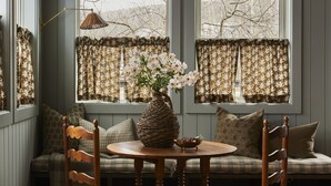 A cozy room with a round wooden table, two chairs, a woven vase with flowers, and a bench with cushions. - The June Motel, Beaver Valley (Grey Highlands)