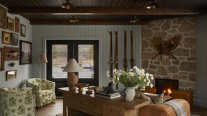 A cozy living room with a fireplace, wooden furniture, and a stone wall. - The June Motel, Beaver Valley (Grey Highlands)