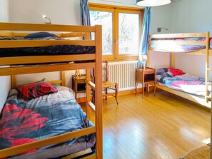 Une chambre avec des lits superposés, un bureau et une chaise.