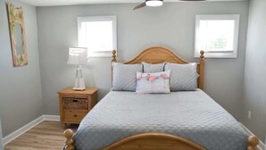 Une chambre à coucher avec un lit en bois, une table de chevet, une lampe et un ventilateur de plafond.