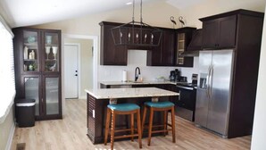 Une cuisine moderne avec des meubles en bois foncé, un réfrigérateur en acier inoxydable et un îlot central doté de tabourets.