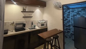A kitchen with a microwave, sink, and bar stools. - Oasis by Franklin #2 (La Fortuna)