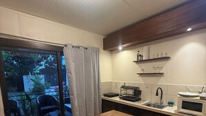 A kitchen with a dining area, a sliding glass door to a balcony, and a microwave. - Oasis by Franklin #2 (La Fortuna)
