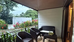 A covered outdoor seating area with wicker furniture, a small table, and a potted plant. - Oasis by Franklin #2 (La Fortuna)