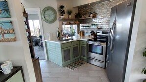 Eine moderne Küche mit Einbauofen, Edelstahlkühlschrank und Deckenventilator.