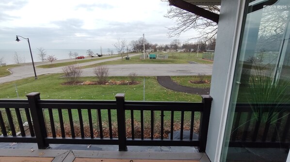 A view from a balcony overlooking a parking lot with a grassy area and a body of water in the background. - The Aloha
overlooking lake erie (Vermilion)