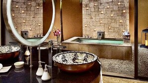 A modern bathroom with a large mirror, two sinks, and a bathtub.
