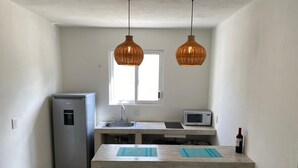 Une petite cuisine équipée d’un réfrigérateur, d’un four à micro-ondes et d’une bouteille de vin posée sur le plan de travail.