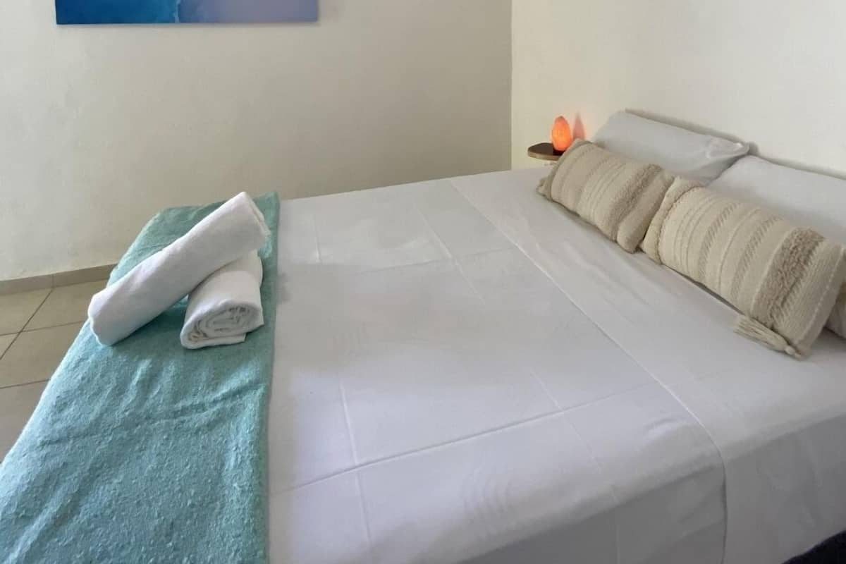 Une chambre d’hôtel avec un lit, une serviette bleue, un oreiller blanc et un appareil de climatisation.